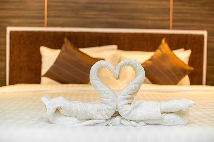Towels folded into a pair of swans on a made bed.