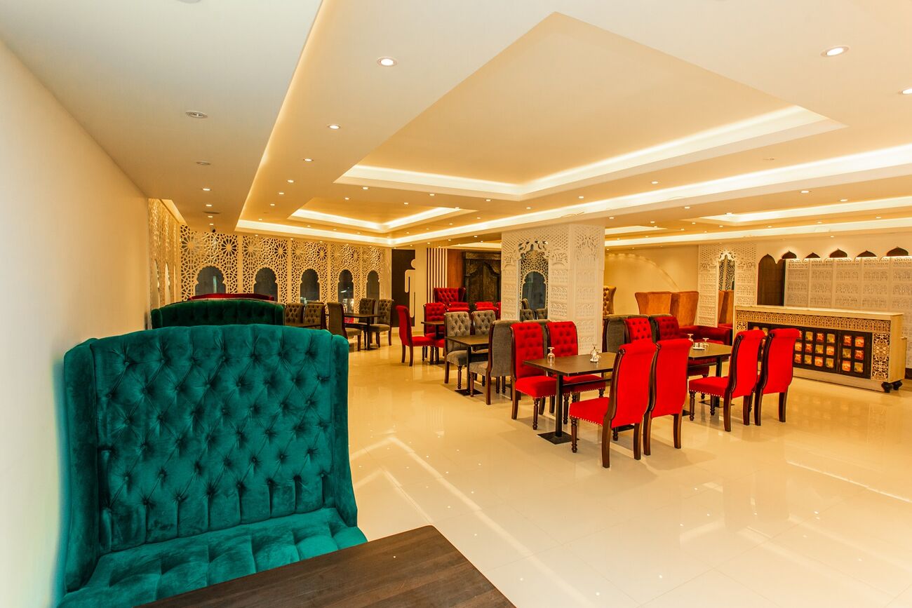 The Royal Saffron dining room, green velvet booths facing rows of red chairs.