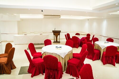Taj hall laid for a lunch with round tables under a chandelier.