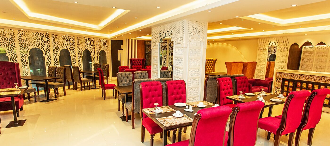 Royal Saffron Restaurant, red velvet chairs under carved gold arches.