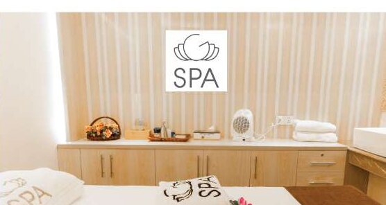 A treatment room at G-Spa, folded towels and a lit SPA panel.