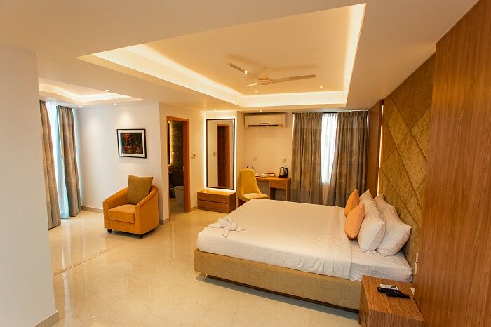A Premium Double room at Royal Raj, wide layout with an armchair by the window.