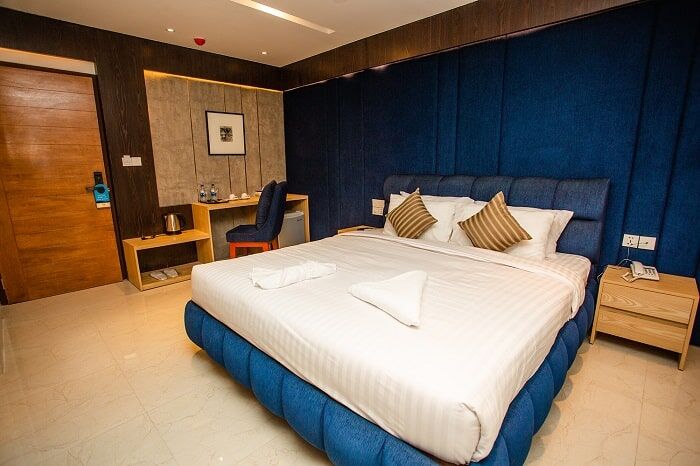 Superior Double room, king bed against a deep blue padded wall.