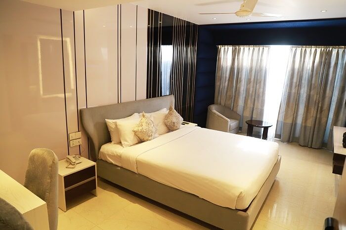 Superior Single room with a padded headboard and full-height curtains.